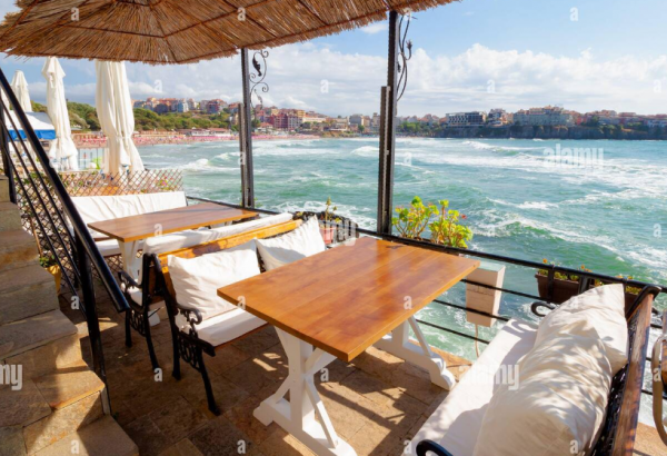 Cafe dengan teras tepi pantai dan meja berpayung